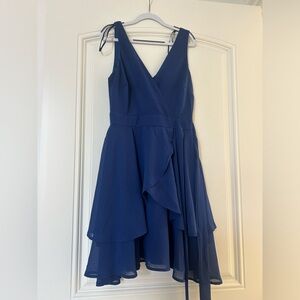 A navy blue flowy wrap around mini dress with a v cut